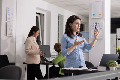 Female friends using mobile phone while standing in gym