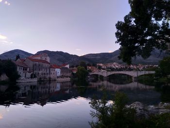 Arch bridge over river by buildings against sky