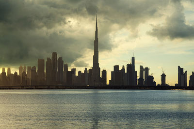 Sea by modern buildings against sky in city