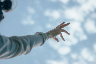 Low angle view of human hand against sky