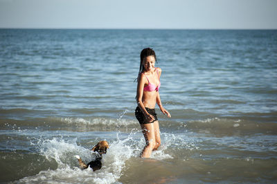 Happy girl with afro hairstyle, playing with a dog on the beach person