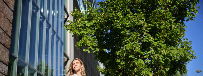 Low angle view of woman standing against trees