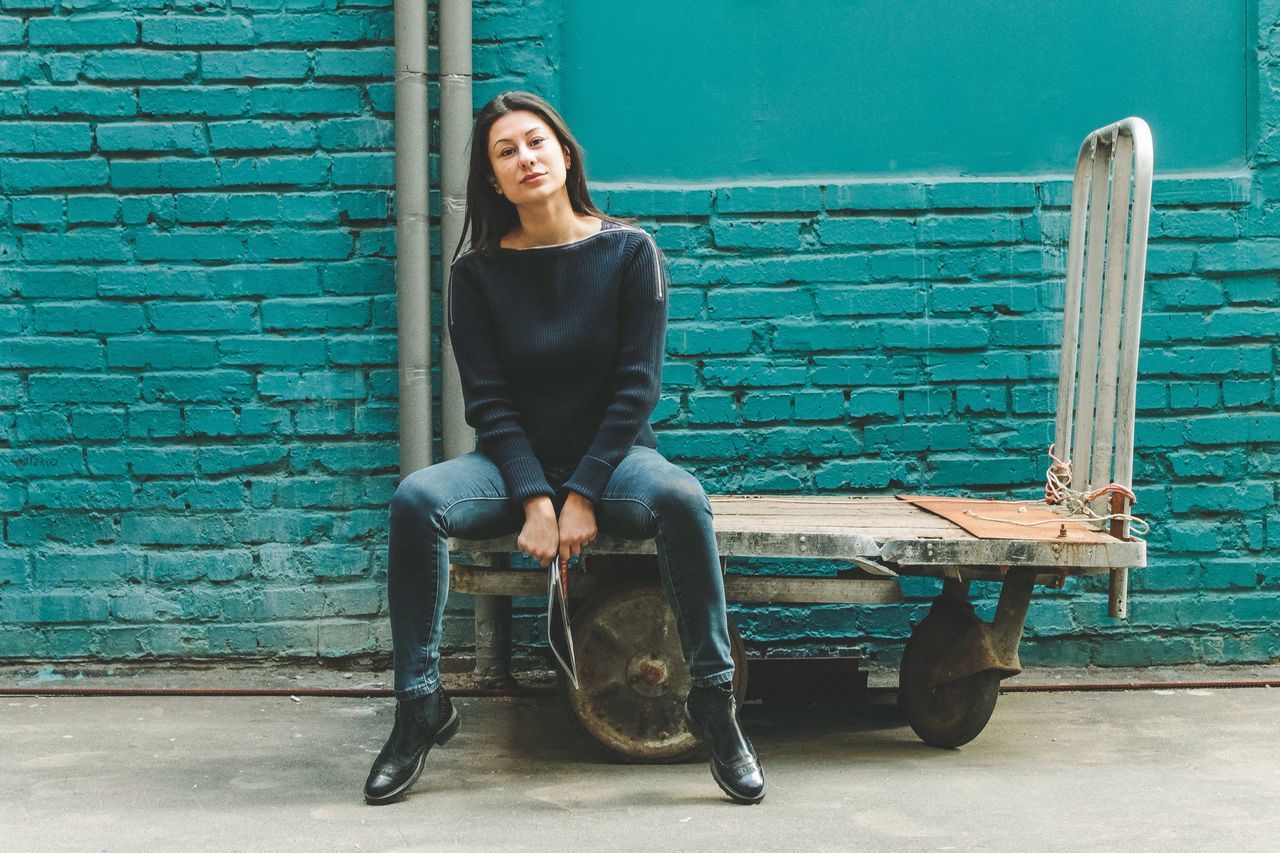 sitting, full length, one woman only, only women, one person, outdoors, adults only, brick wall, beautiful people, leisure activity, people, city, adult, day, women, young women, young adult, one young woman only