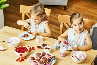 Mother and daughter sitting on table