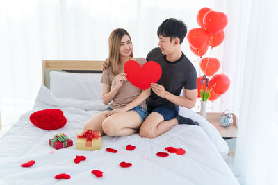 Couple sitting on red balloons