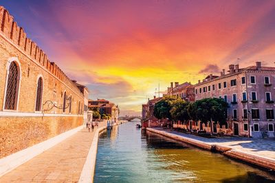 Canal passing through city buildings during sunset