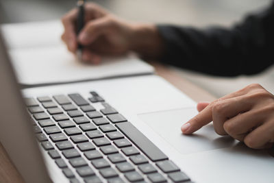 Cropped hands of businessman using laptop on table