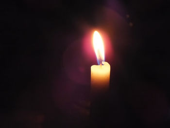 Close-up of lit candle in dark room