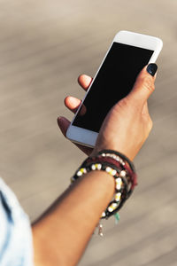 Cropped hand of young woman using smart phone