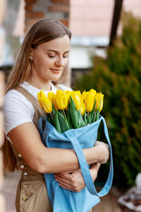 Portrait of a happy female florist with a bouquet of yellow tulips. women's day, valentine's day