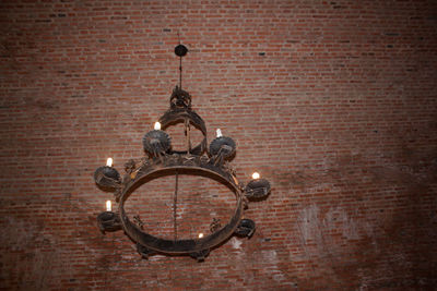 Close-up of illuminated street light against brick wall cast iron lamp