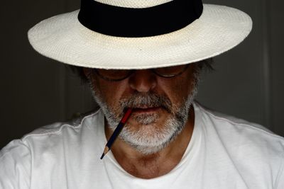 Close-up of mature man wearing hat against wall