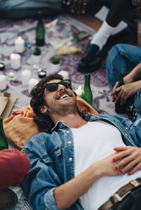 High angle view of smiling man lying down on picnic blanket at rooftop party