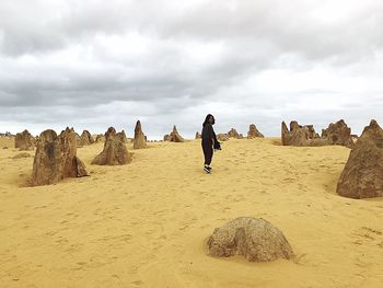 Rear view of man on rock formations against sky