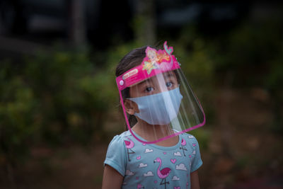 Portrait of cute girl wearing face mask standing outdoors