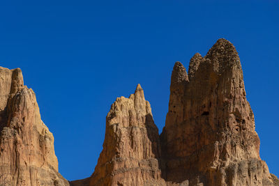 Low angle view of rock formation against clear blue sky