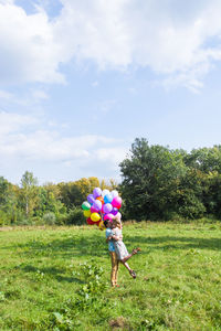 Woman with arms raised on field against sky