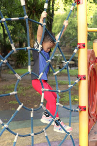 Side view of boy hanging on rope in playground