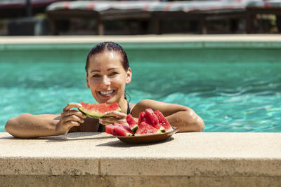 Portrait of smiling girl eating food in swimming pool