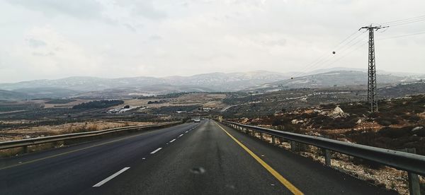 Road leading towards mountains against sky