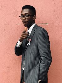 Portrait of young man standing against wall