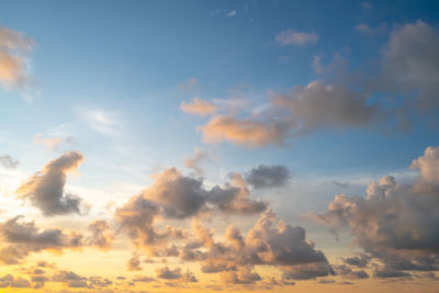 Low angle view of sunlight streaming through clouds during sunset