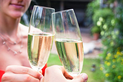 Cropped hands of friends toasting champagne flutes in yard