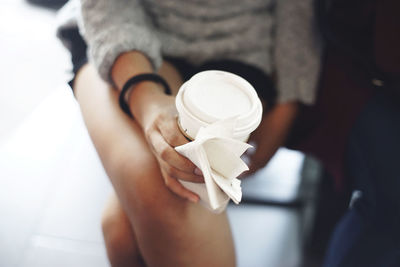 Midsection of woman holding disposable cup and tissue paper