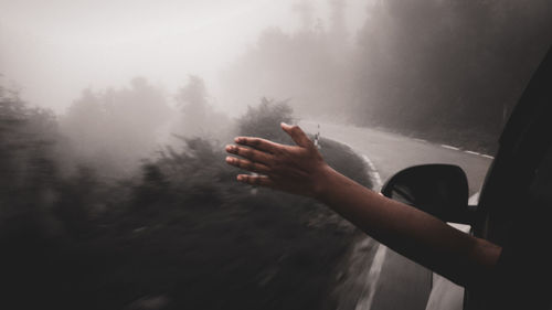 Person hand on wet glass during rainy season