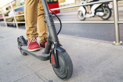 Man with electric scooter in the city, partial view