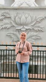 Portrait of young woman standing against wall