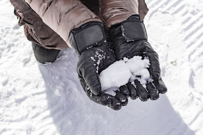 Midsection of person holding snow in hand outdoors