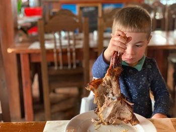 High angle view of boy eating meat while sitting at home