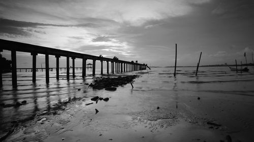 Pier on beach against sky