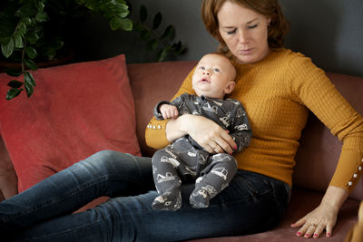 Mother and baby girl sitting on sofa at home