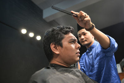 Barber cutting hair of customer at salon