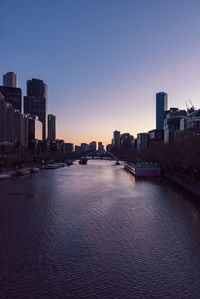River by buildings against sky at sunset