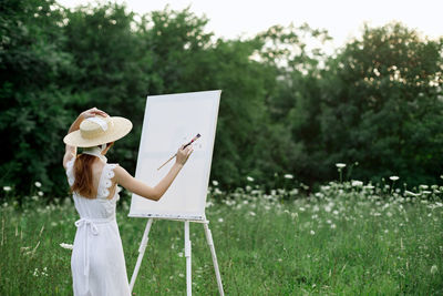 Woman holding umbrella standing on field