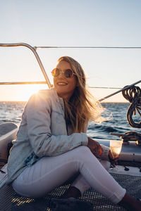 Woman sitting in boat on sea against sky