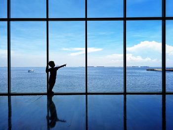 Boy looking at sea through window