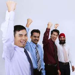 Portrait of smiling businessmen clenching fists against white background