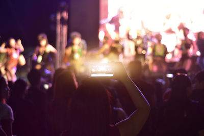Rear view of woman using mobile phone at music concert