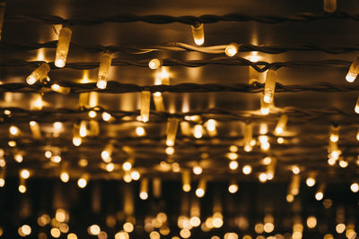 Close-up of illuminated light bulbs hanging from ceiling