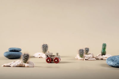 Background image of wooden toy steam locomotive in desert with stones and cactuses on beige backdrop