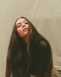 Portrait of beautiful young woman against beige backdrop