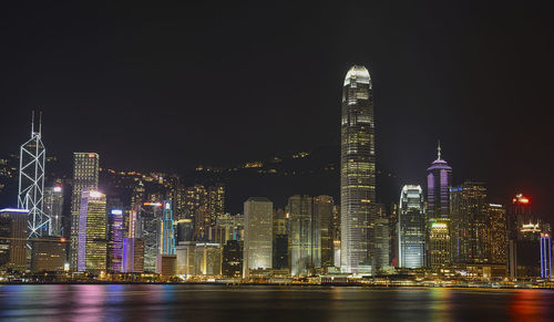 Illuminated modern buildings in city against sky at night