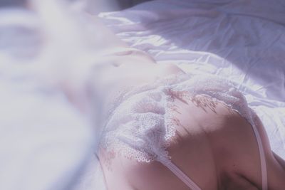 Close-up high angle view of seductive woman wearing lingerie while lying on bed