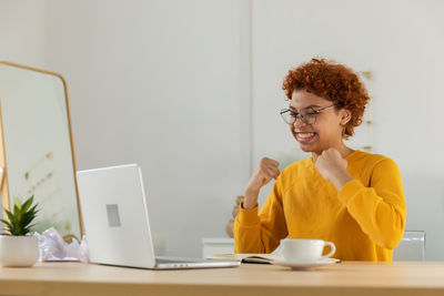 Young woman using mobile phone at table