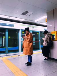 Rear view of people standing on railroad station