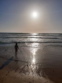 Silhouette people on beach against sky during sunset